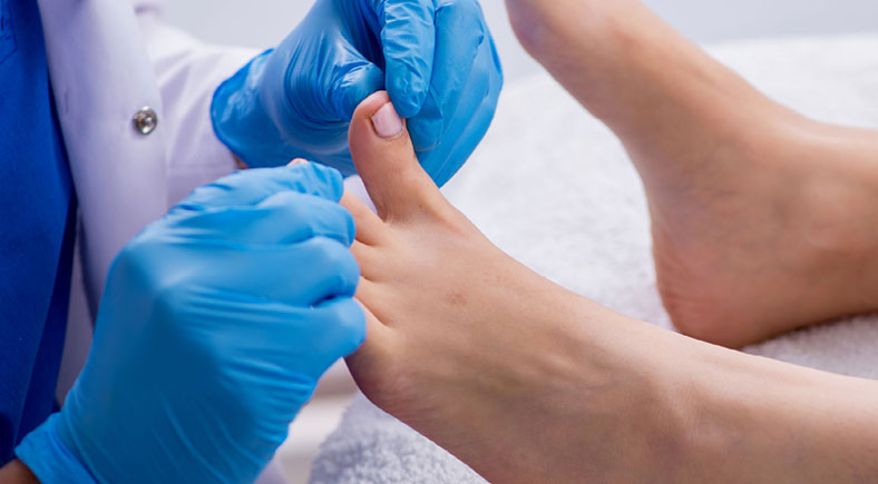 Healthcare professional wearing gloves performing a detailed foot checkup for a patient.