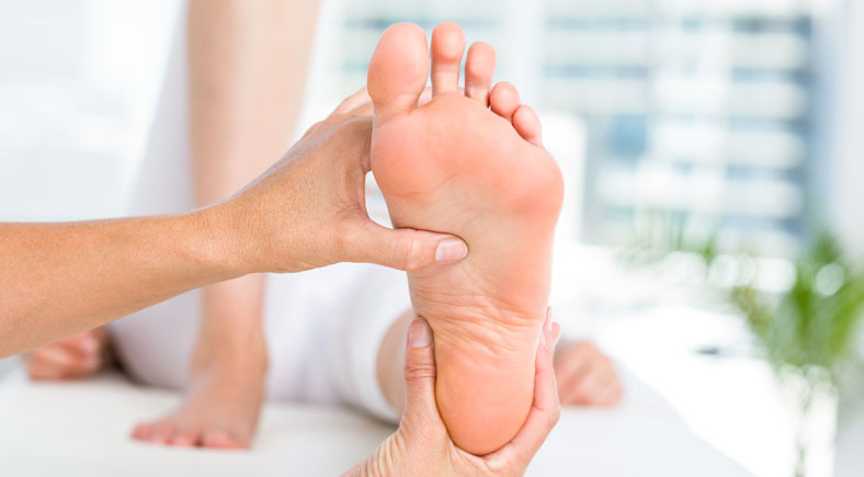 A professional therapist examining the sole of a foot, focusing on foot health and therapy at Foot & Wound Institute.