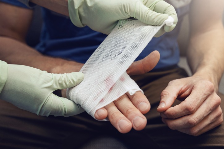 Medical professional bandaging a hand wound with sterile gauze